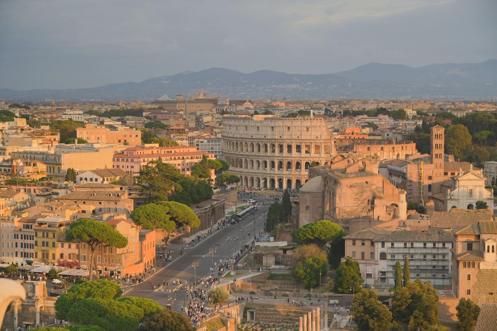 A breathtaking aerial view of Rome, featuring the iconic Colosseum bathed in sunset light