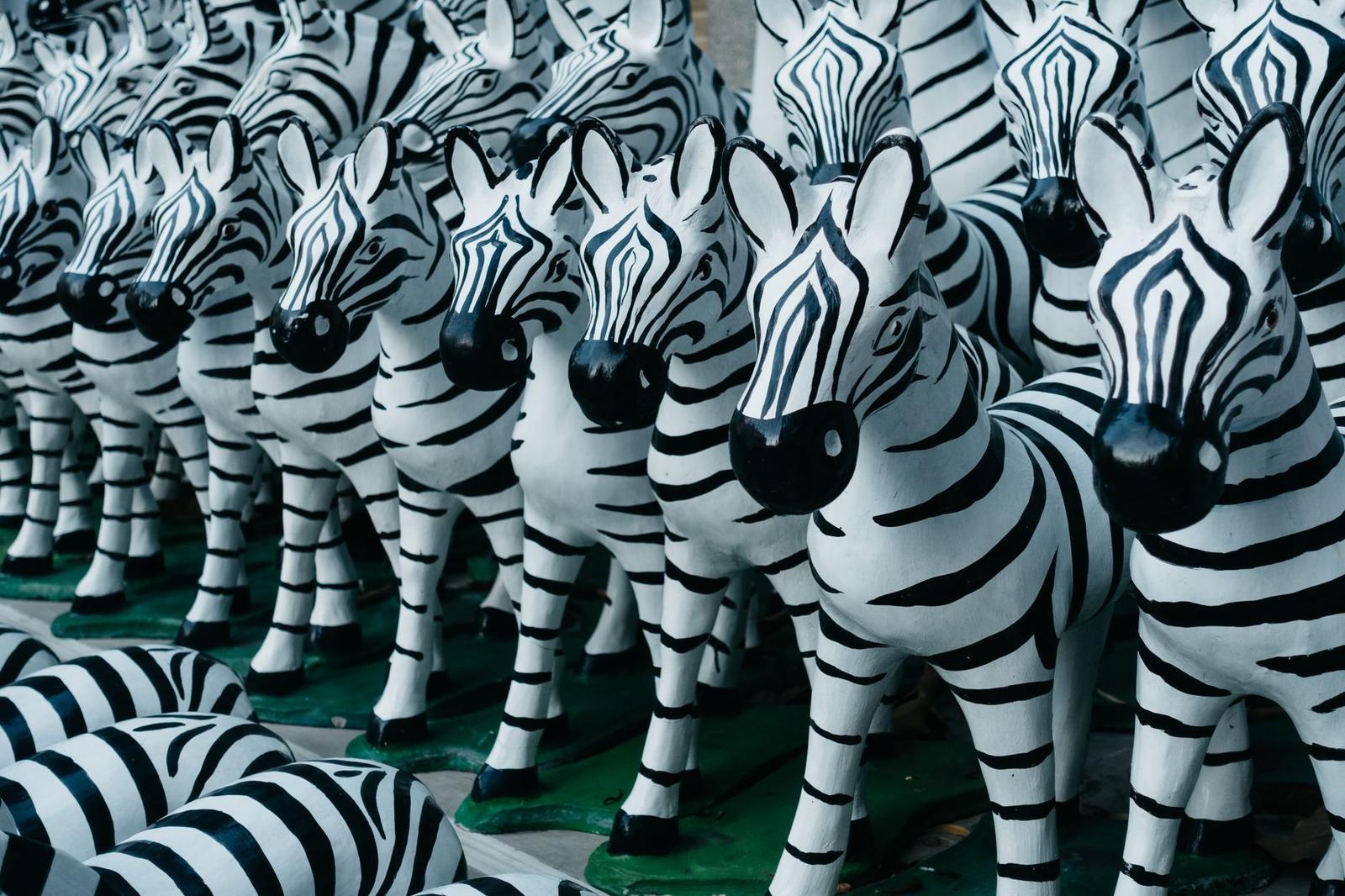 A group of striped zebra statues arranged in a row, displayed outdoors in Bangkok