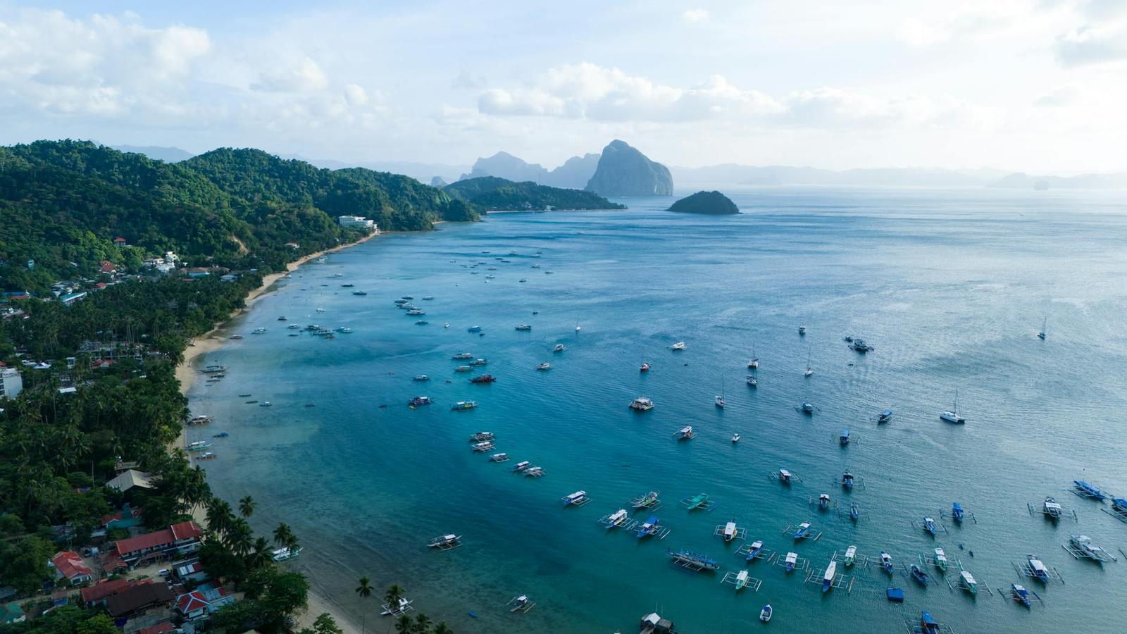 Aerial view of boats anchored in a bay beside limestone islands