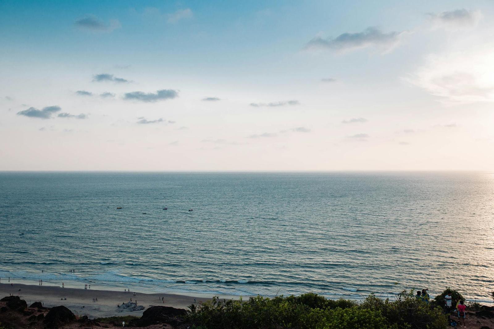 A hazy sea horizon meeting a quiet beach at dusk