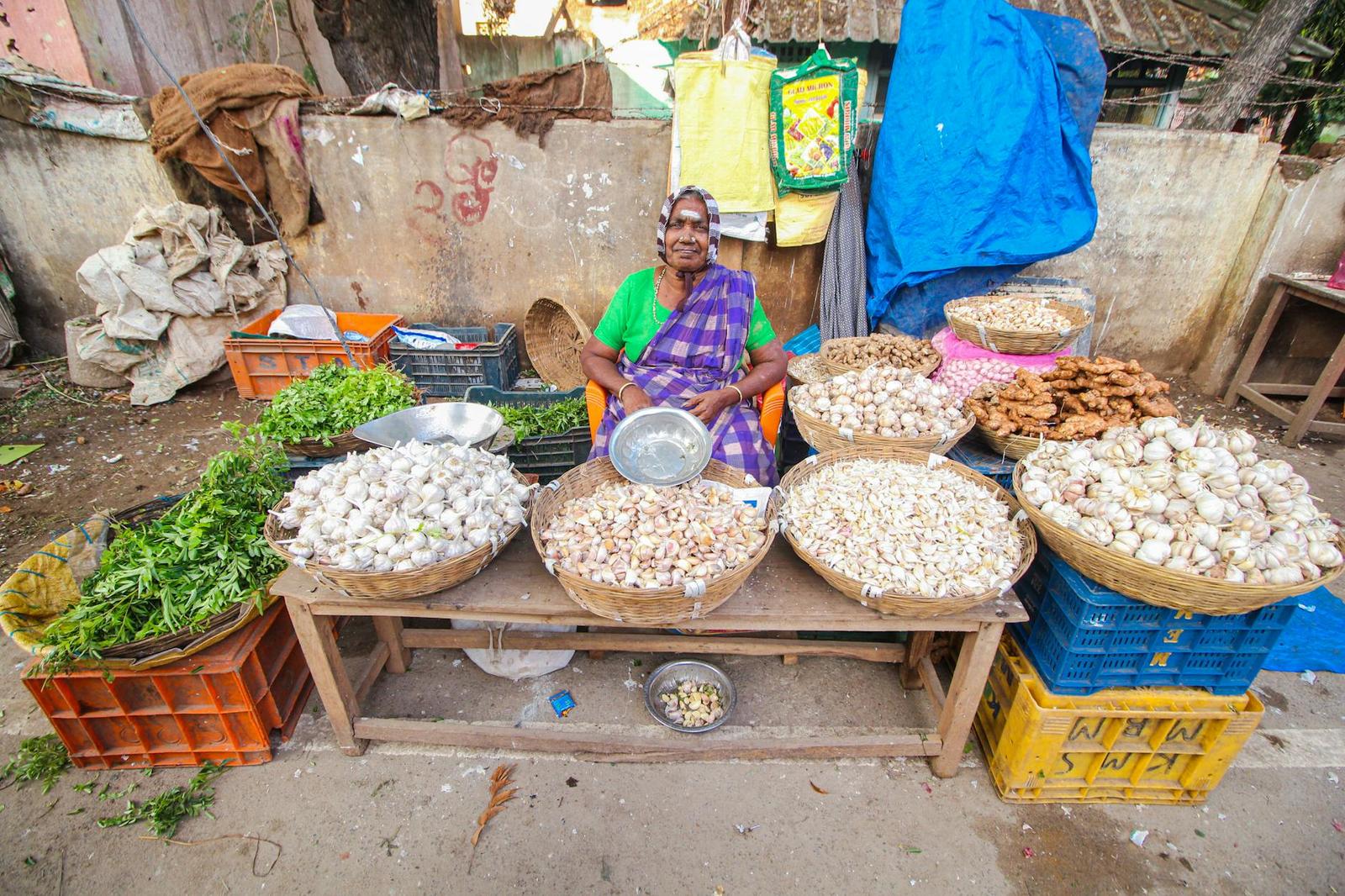 Colorful street market scene of a senior vendor selling vegetables in Cumbum, India