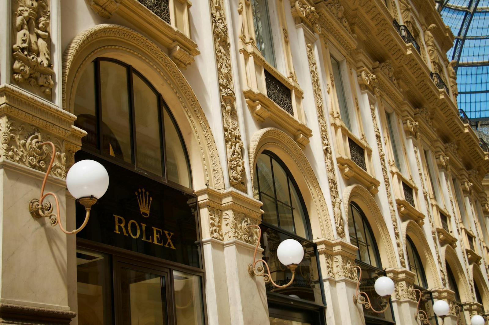 An ornate gilded arcade facade with globe lamps and glass ceiling above