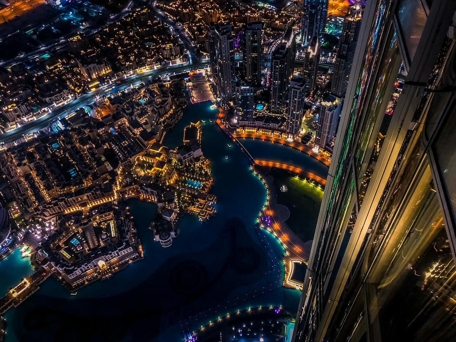 Aerial night view of an illuminated waterfront district with towers and lit walkways