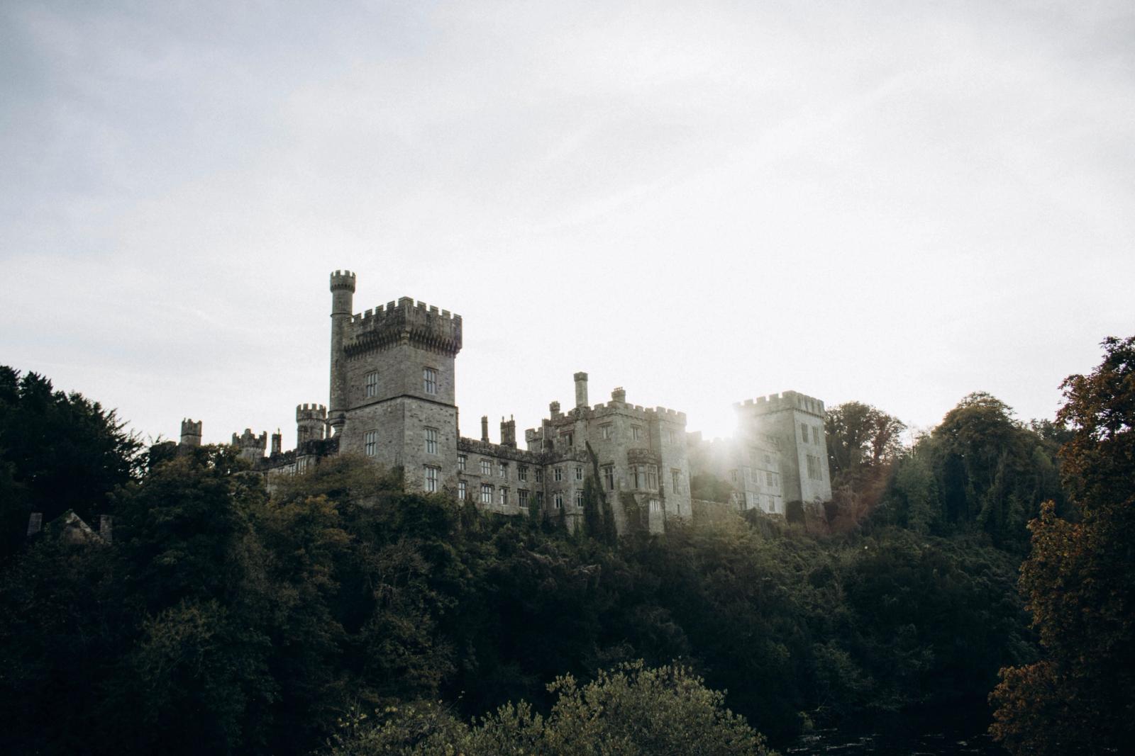 Majestic view of Lismore Castle surrounded by lush greenery at sunrise in Ireland