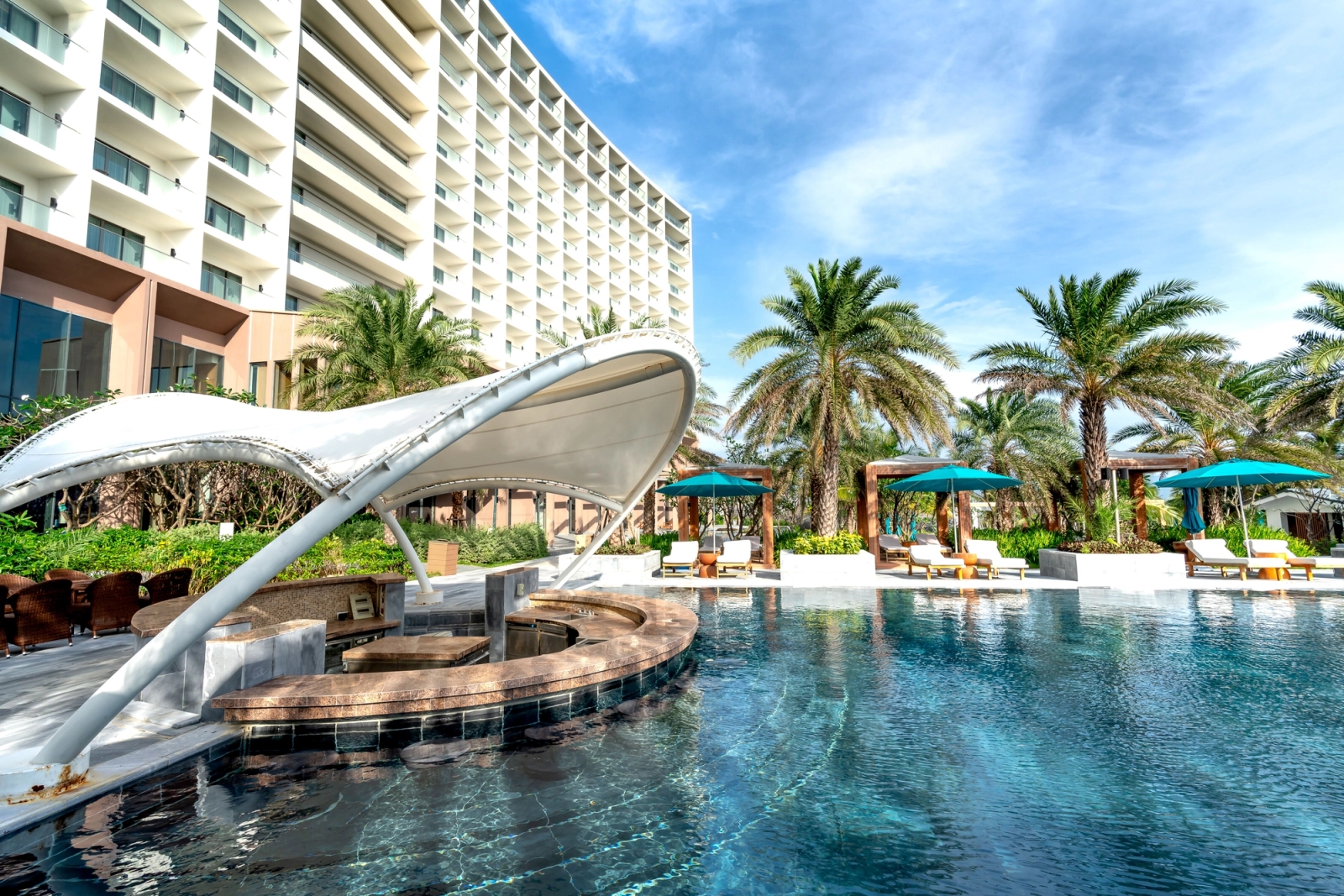 Stunning view of a luxury resort with poolside cabanas, palm trees, and modern architecture