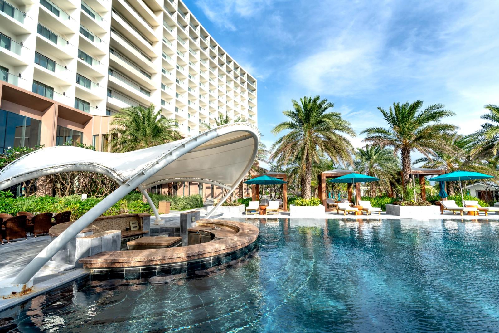 Stunning view of a luxury resort with poolside cabanas, palm trees, and modern architecture