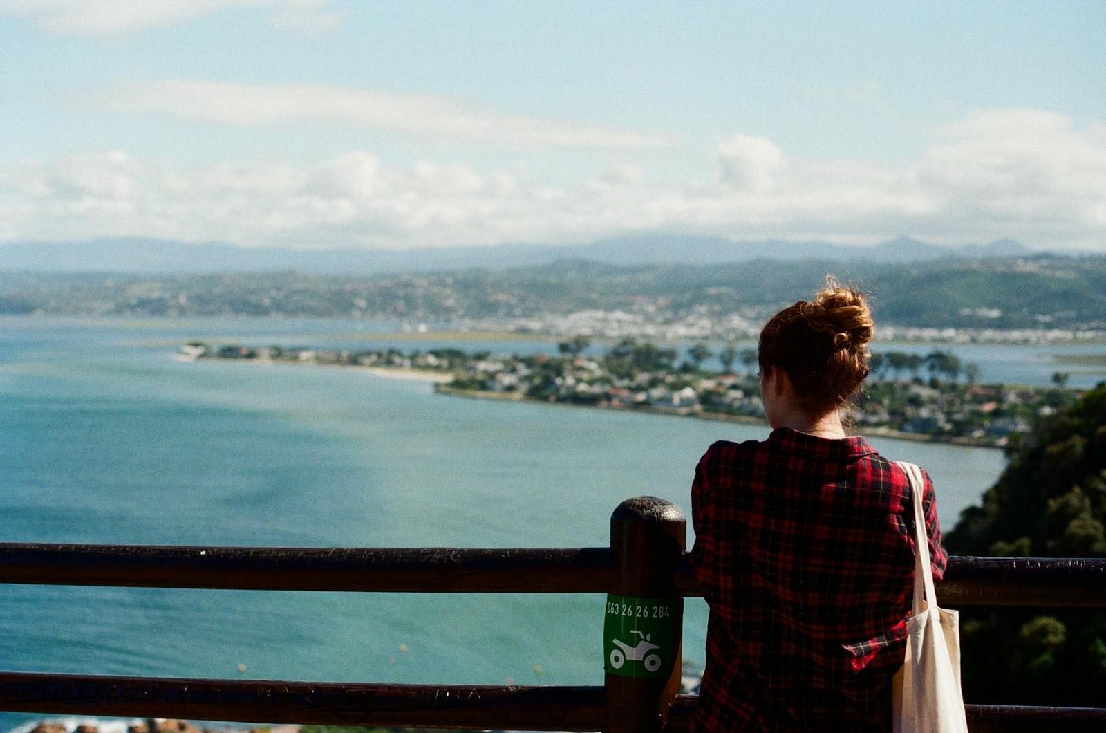 Woman looking out over a coastal lagoon from a railing viewpoint