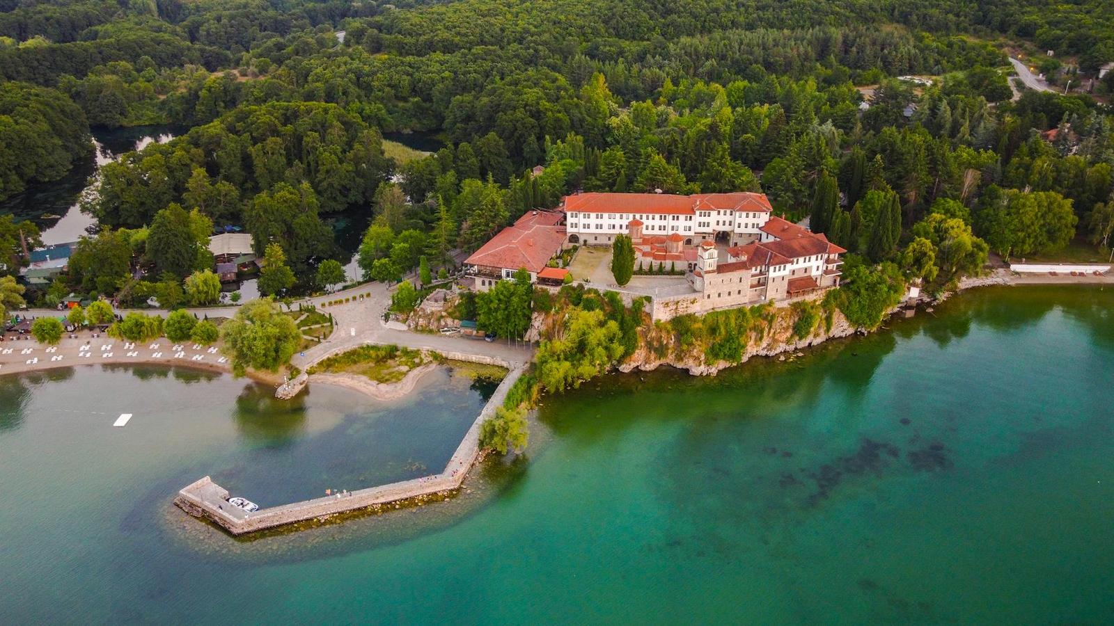 Aerial view of a grand lakeside villa on a rocky point with a jetty