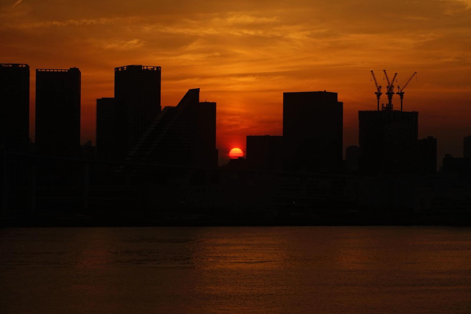 Silhouette of Tokyo skyline with a vibrant sunset and ocean view, capturing urban beauty