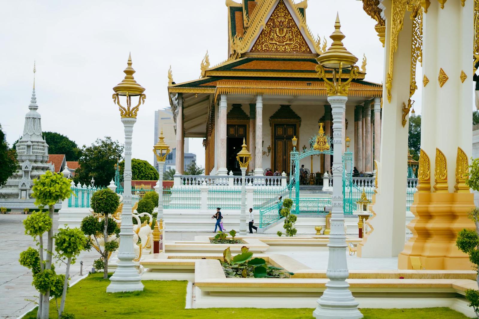 A gilded temple pavilion with ornate spires and lamp posts in a palace courtyard