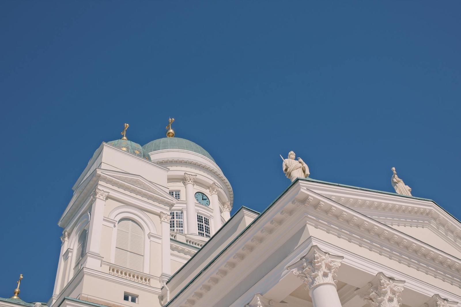 A white domed cathedral roof with statues against a deep blue sky