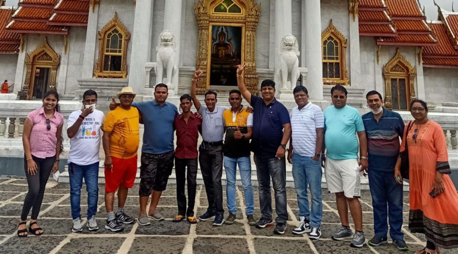 Group pf people posing for a photo in front of a temple.