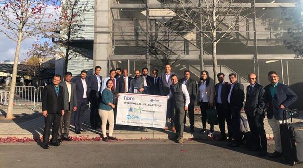 A group of professionals posing outdoors with a banner.