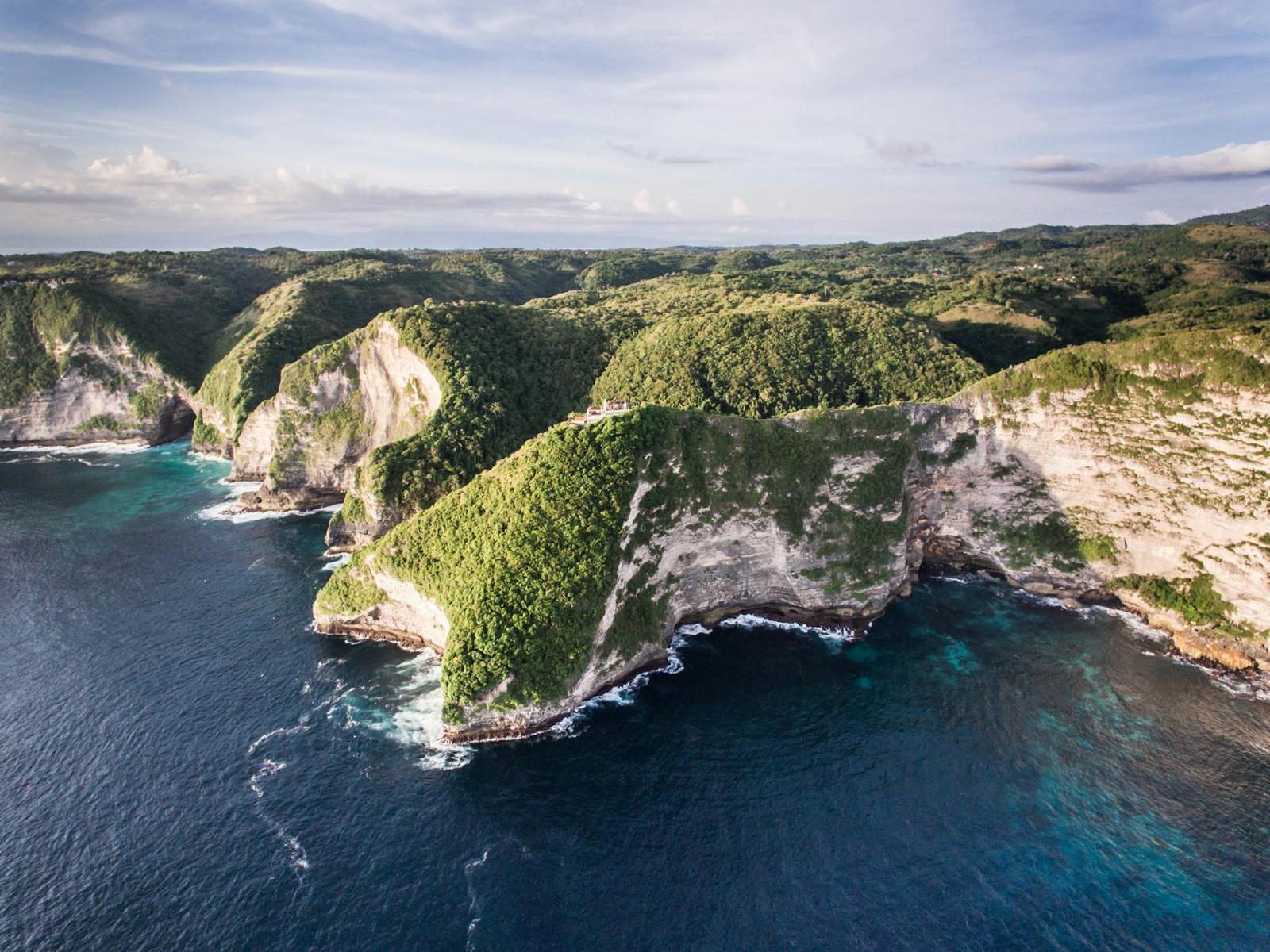 Aerial view of rugged green coastal cliffs meeting deep blue sea