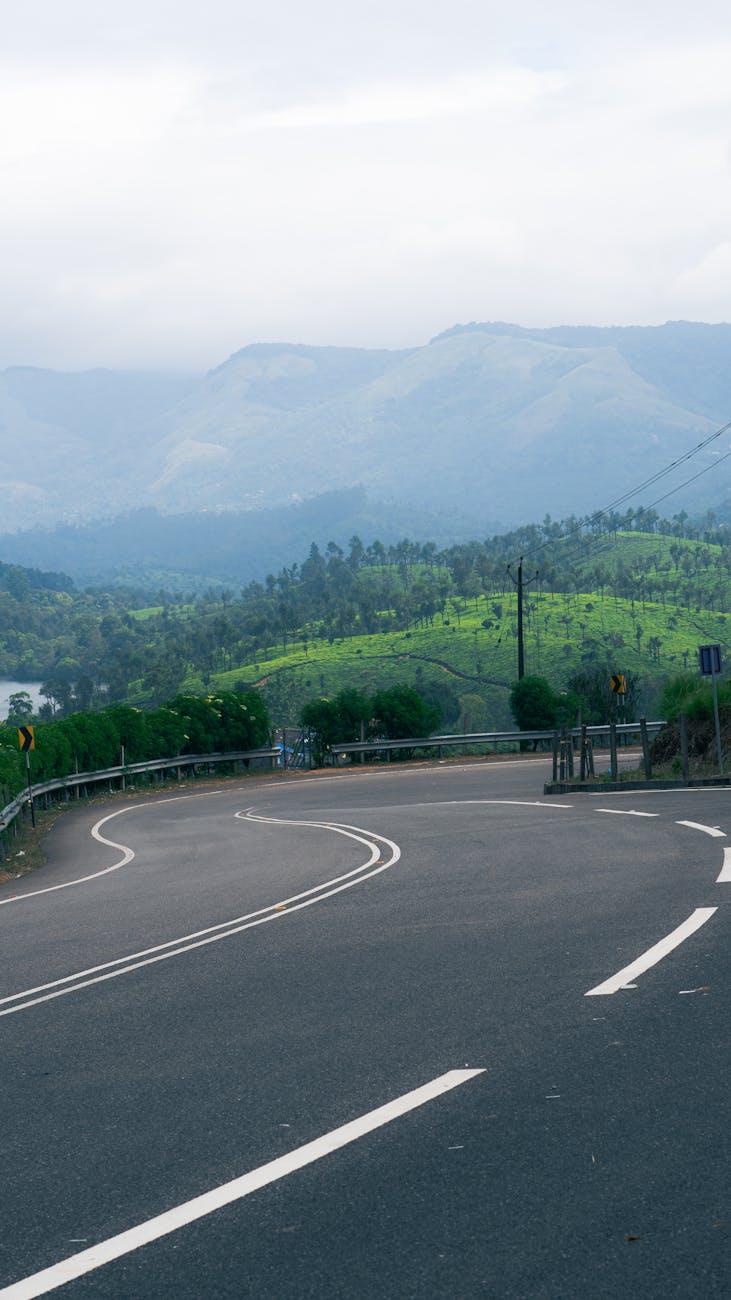 Winding road through lush greenery with distant mountains in Kerala, India