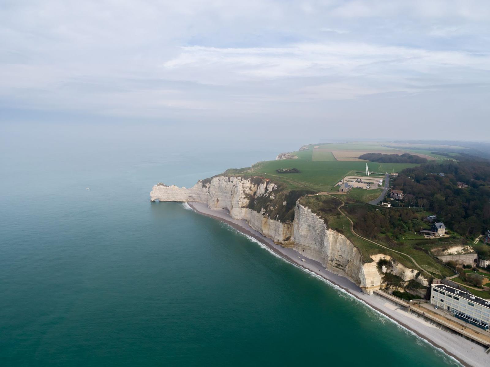 White chalk sea cliffs with a natural arch rising above a pebble beach