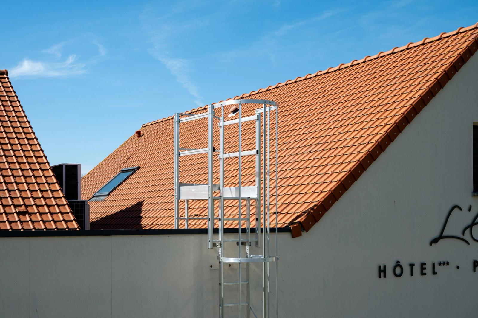 Sunny view of a hotel rooftop with ladder, featuring terracotta tiles and blue sky in Escalles, France