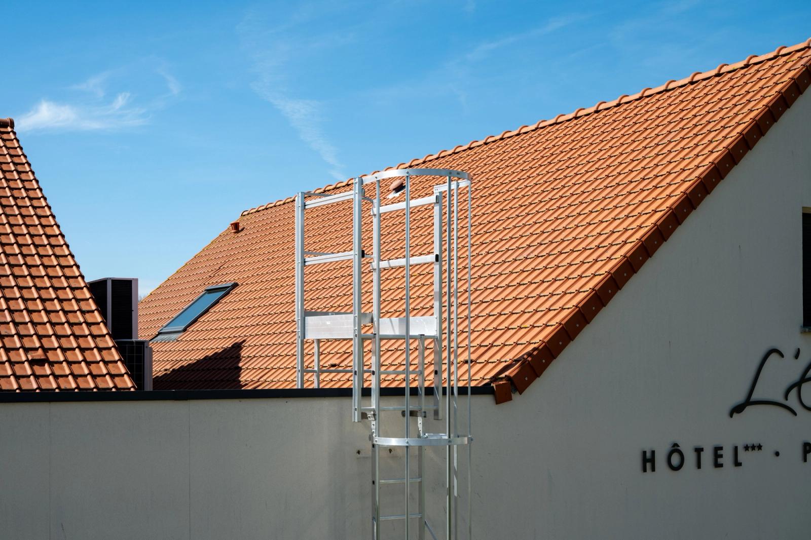Sunny view of a hotel rooftop with ladder, featuring terracotta tiles and blue sky in Escalles, France