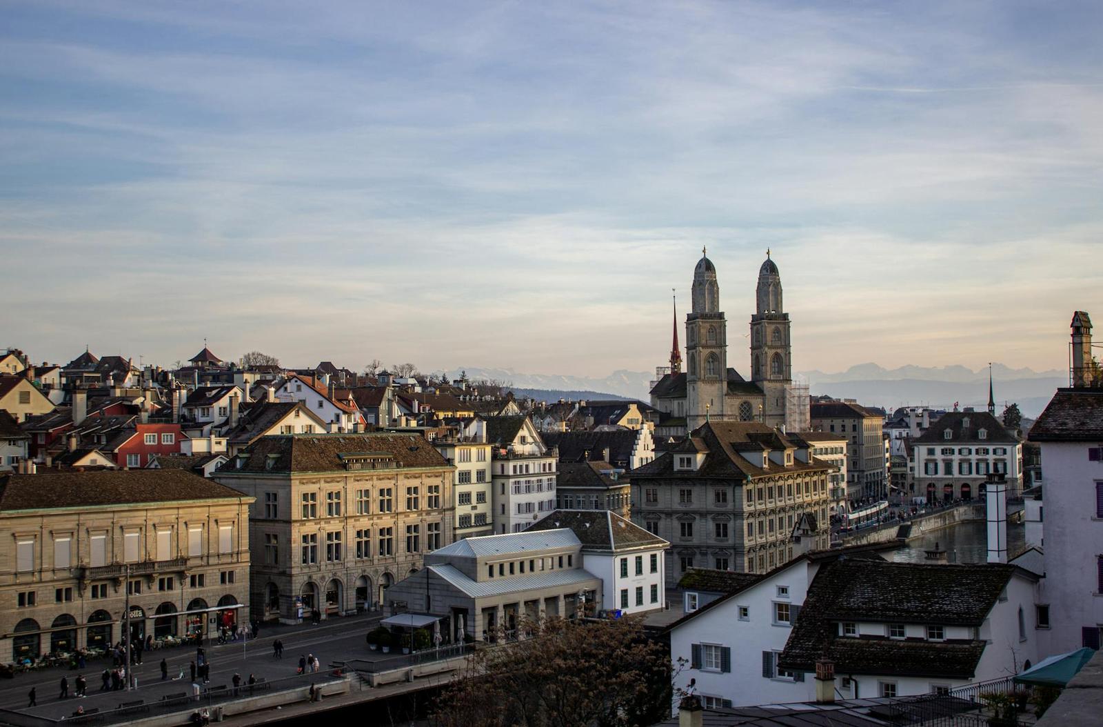 Old town rooftops beneath twin church towers at golden hour
