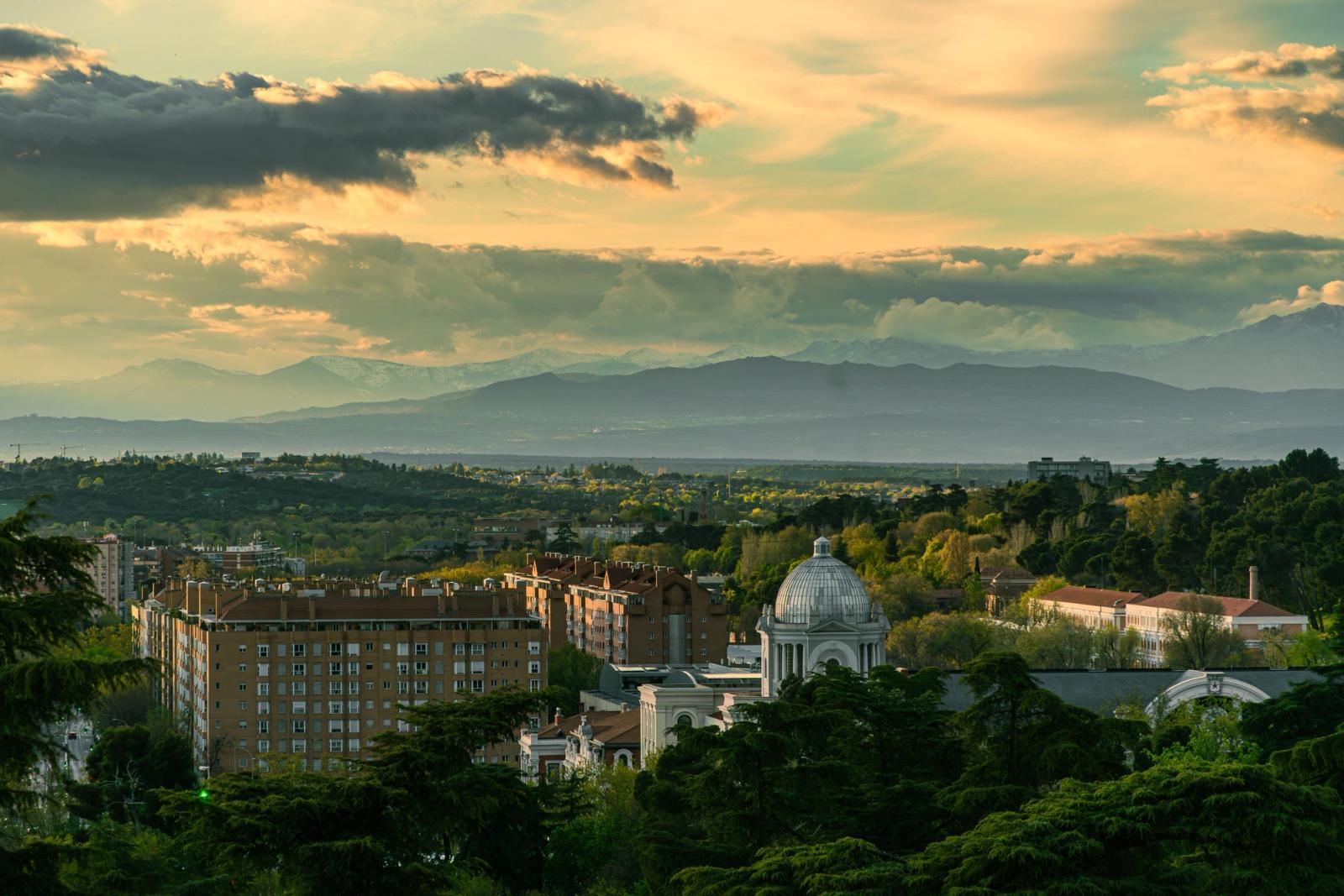 Panoramic view of Madrid's urban landscape with mountains and a dramatic sky at dusk