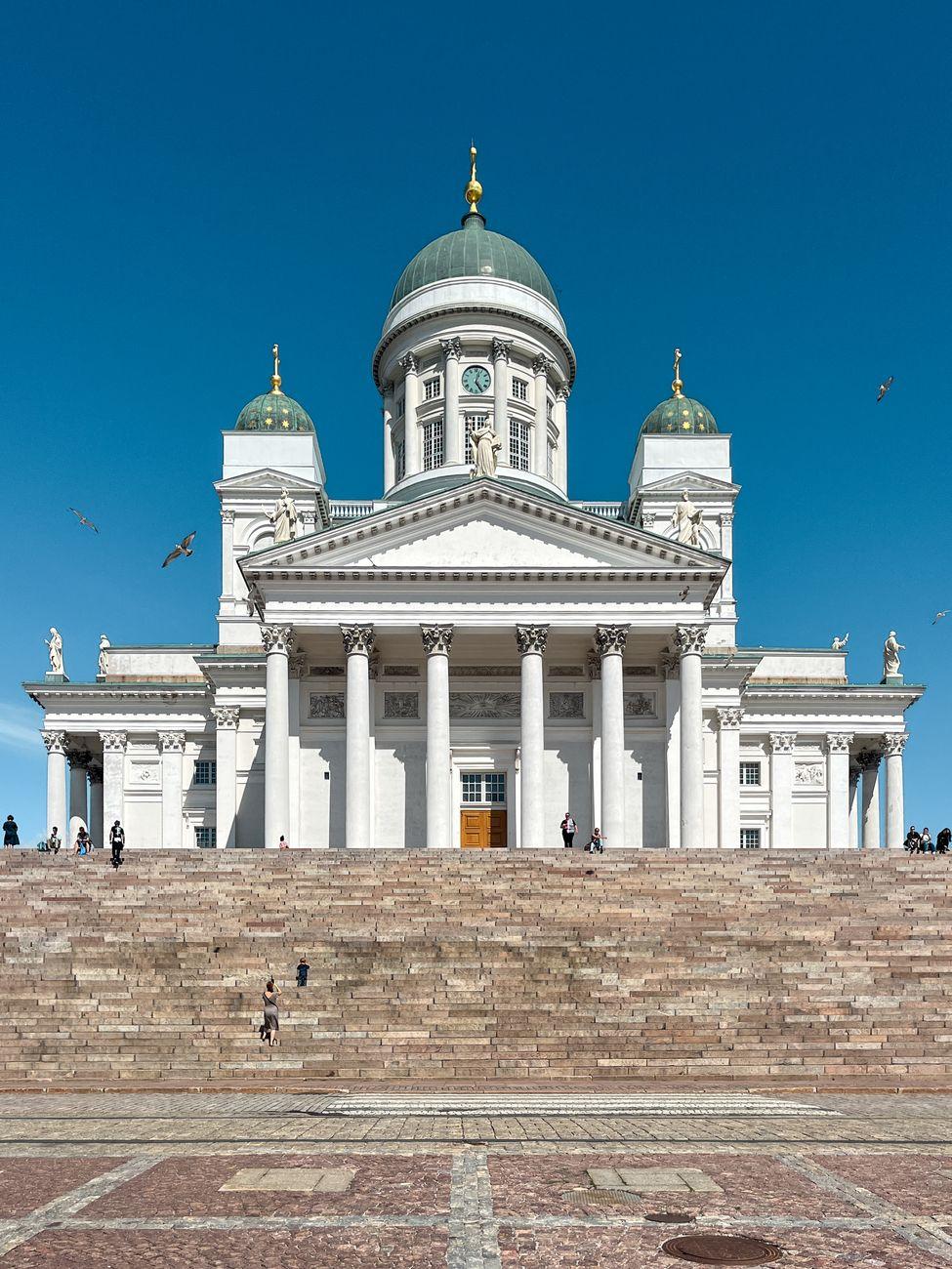A sunlit view of the iconic Helsinki Cathedral with a clear blue sky in the background