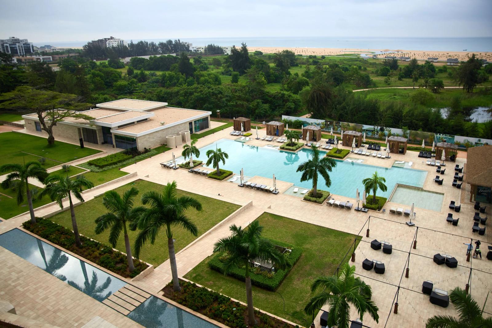Aerial view of a luxury resort pool area with lush greenery and beach access