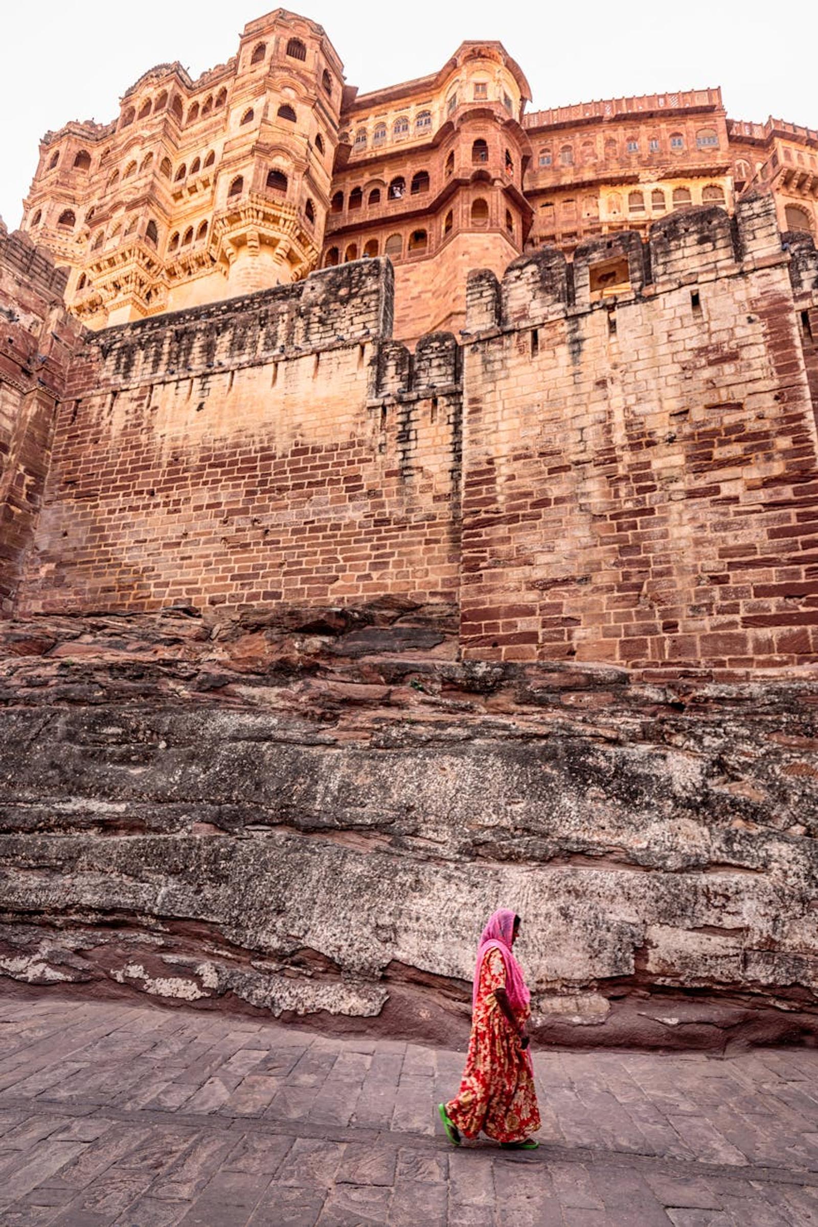 A woman in traditional attire walking near the historic Mehrangarh Fort in India