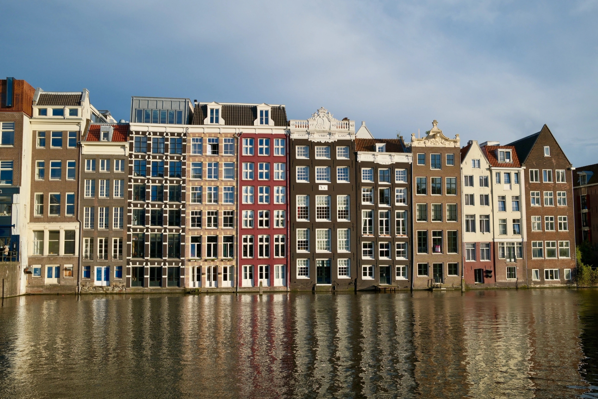 Elegant row of historic Amsterdam canal houses reflecting in a calm waterway