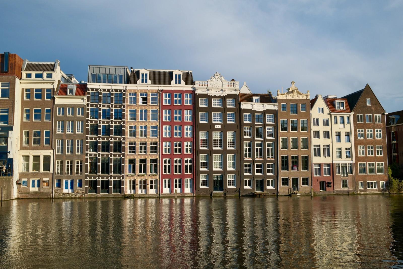 Elegant row of historic Amsterdam canal houses reflecting in a calm waterway