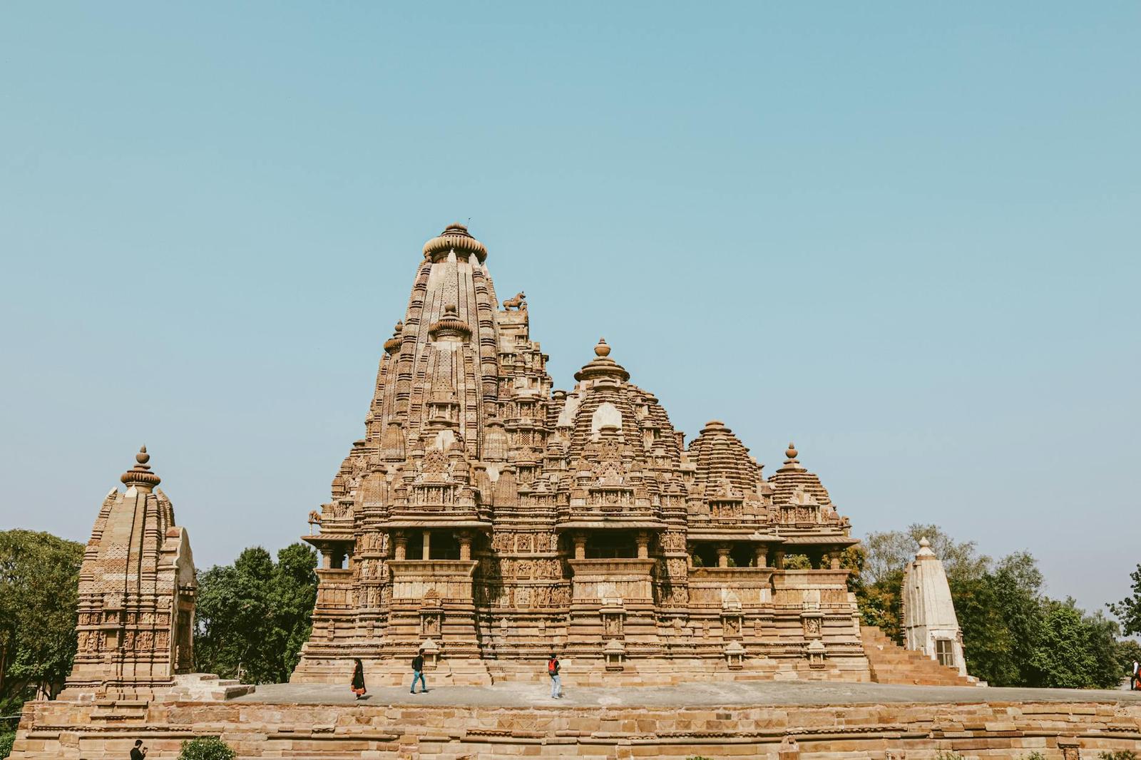A stone temple with a tall curved spire set against a pale sky