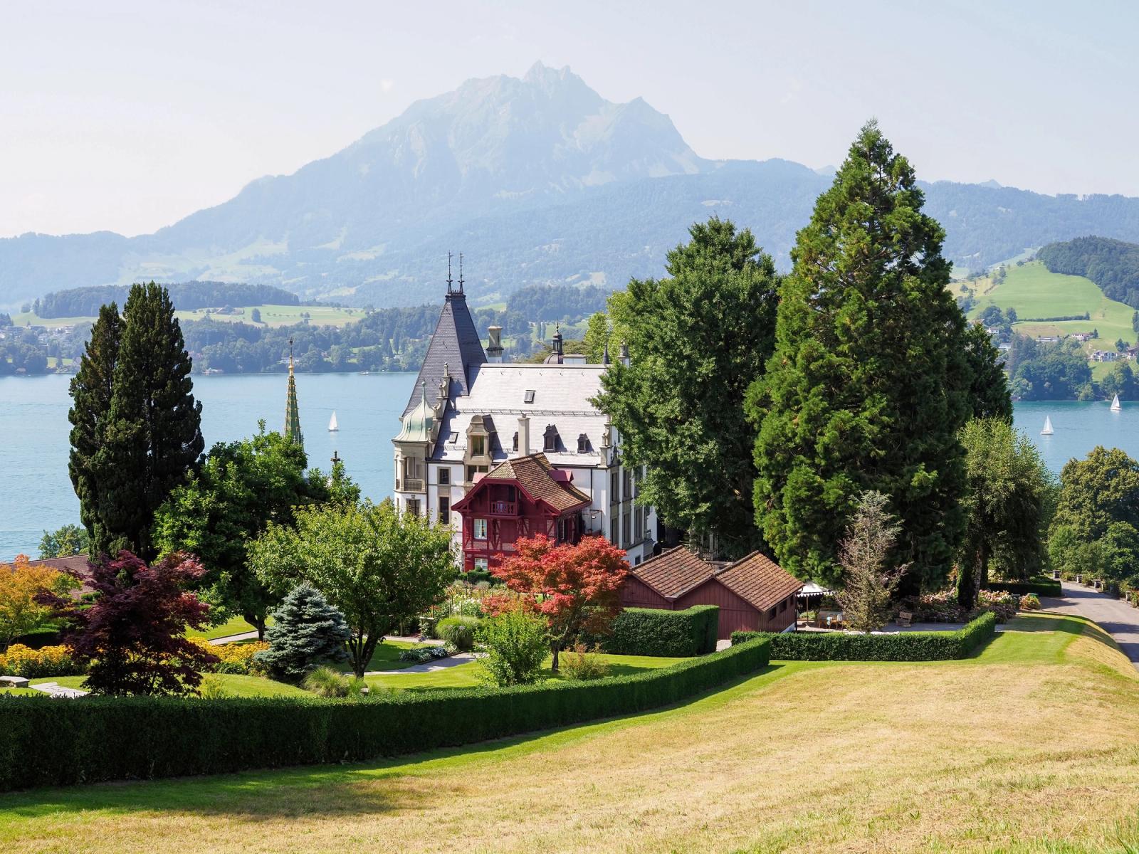 Charming Swiss castle by a serene lake and majestic mountain backdrop in summer
