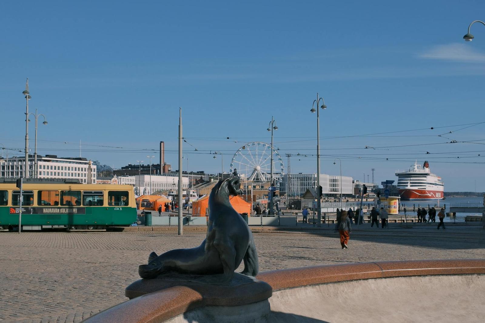 Harbourside square with a seal statue, tram and ferris wheel