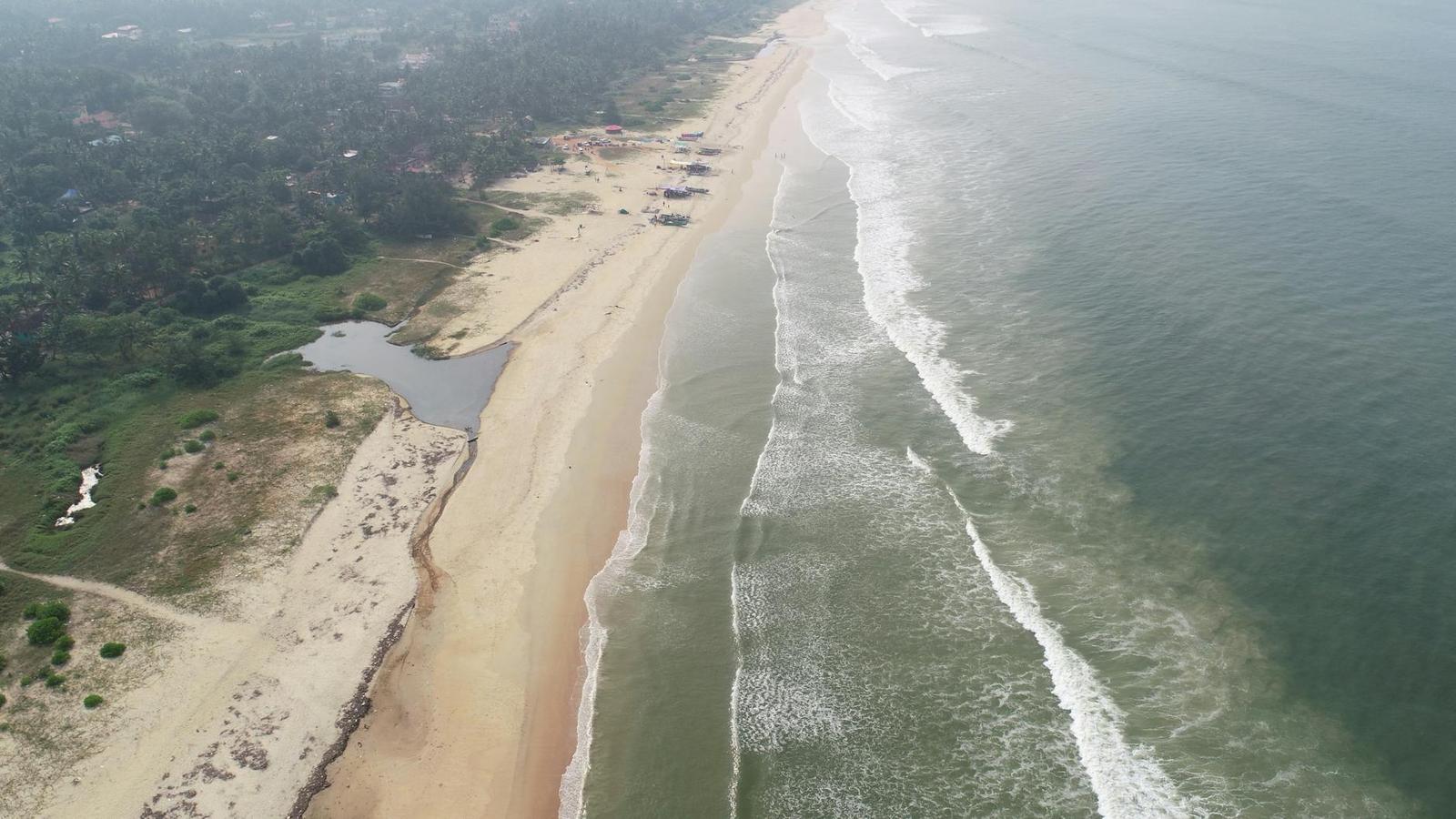 Aerial view of a misty coastline where a lagoon meets breaking surf