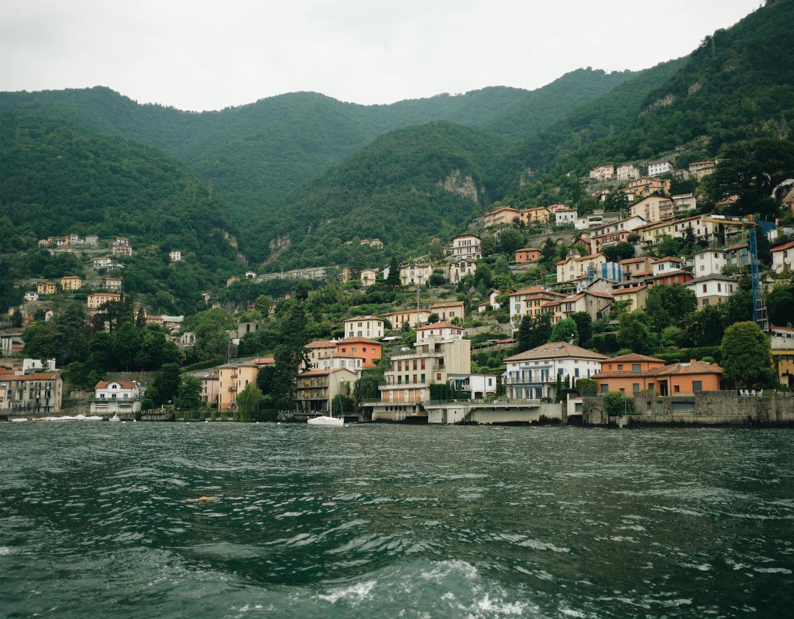 A lakeside village of terracotta rooftops climbing a forested hillside