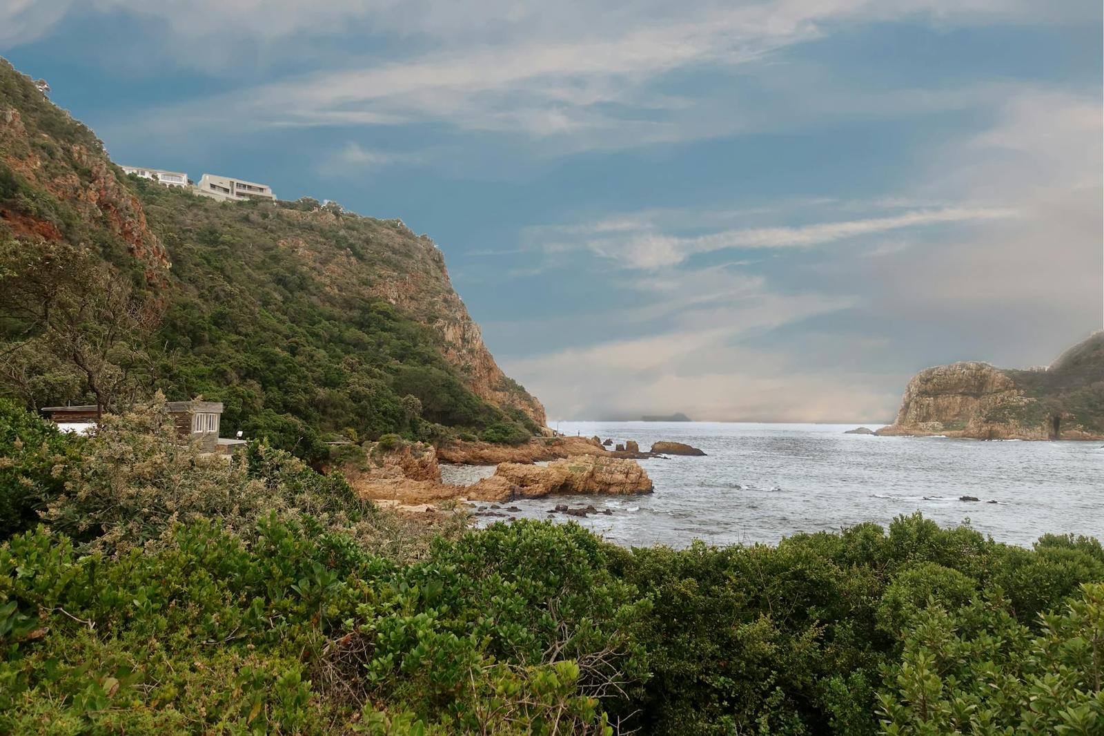 Houses perched atop rocky sea cliffs above a rugged coastal inlet