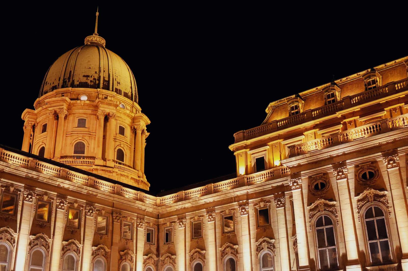 A grand palace dome and colonnade illuminated in warm light at night