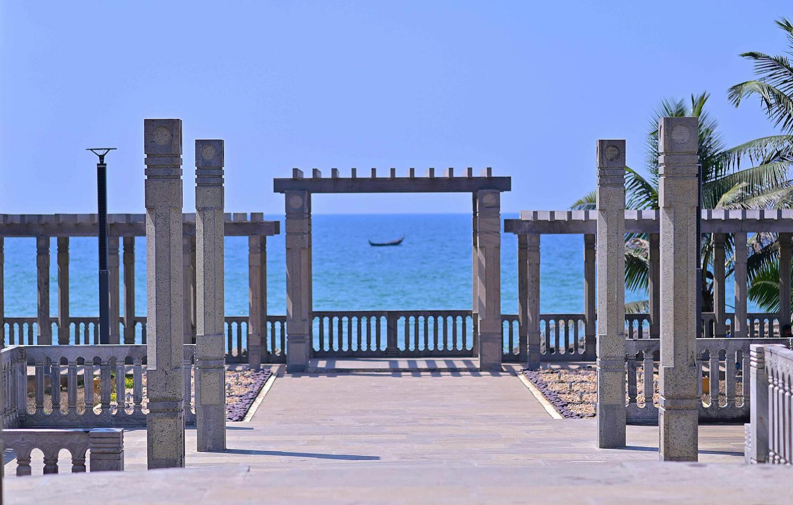 A stone pillared pavilion framing a view of the sea and a fishing boat