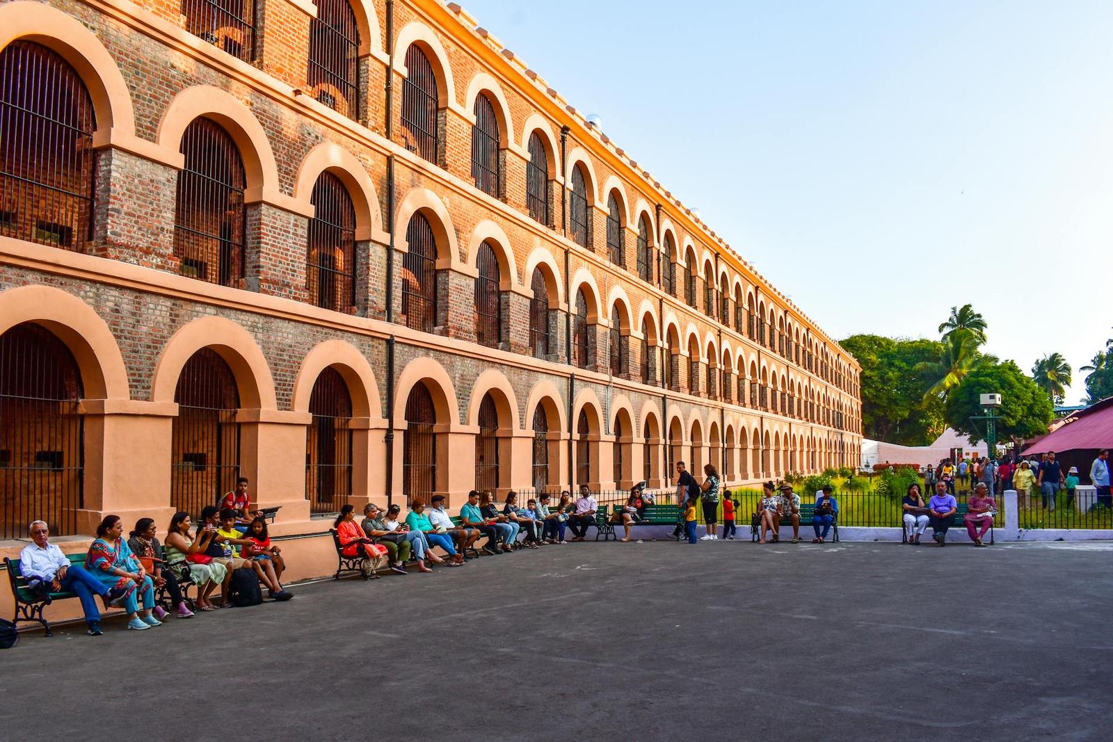 Visitors seated on benches before a tiered arched colonial facade