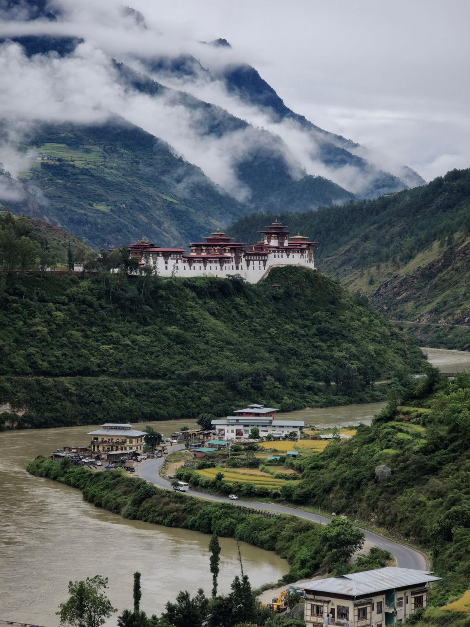 Majestic view of Punakha Dzong with clouds and river in Bhutan's lush landscape