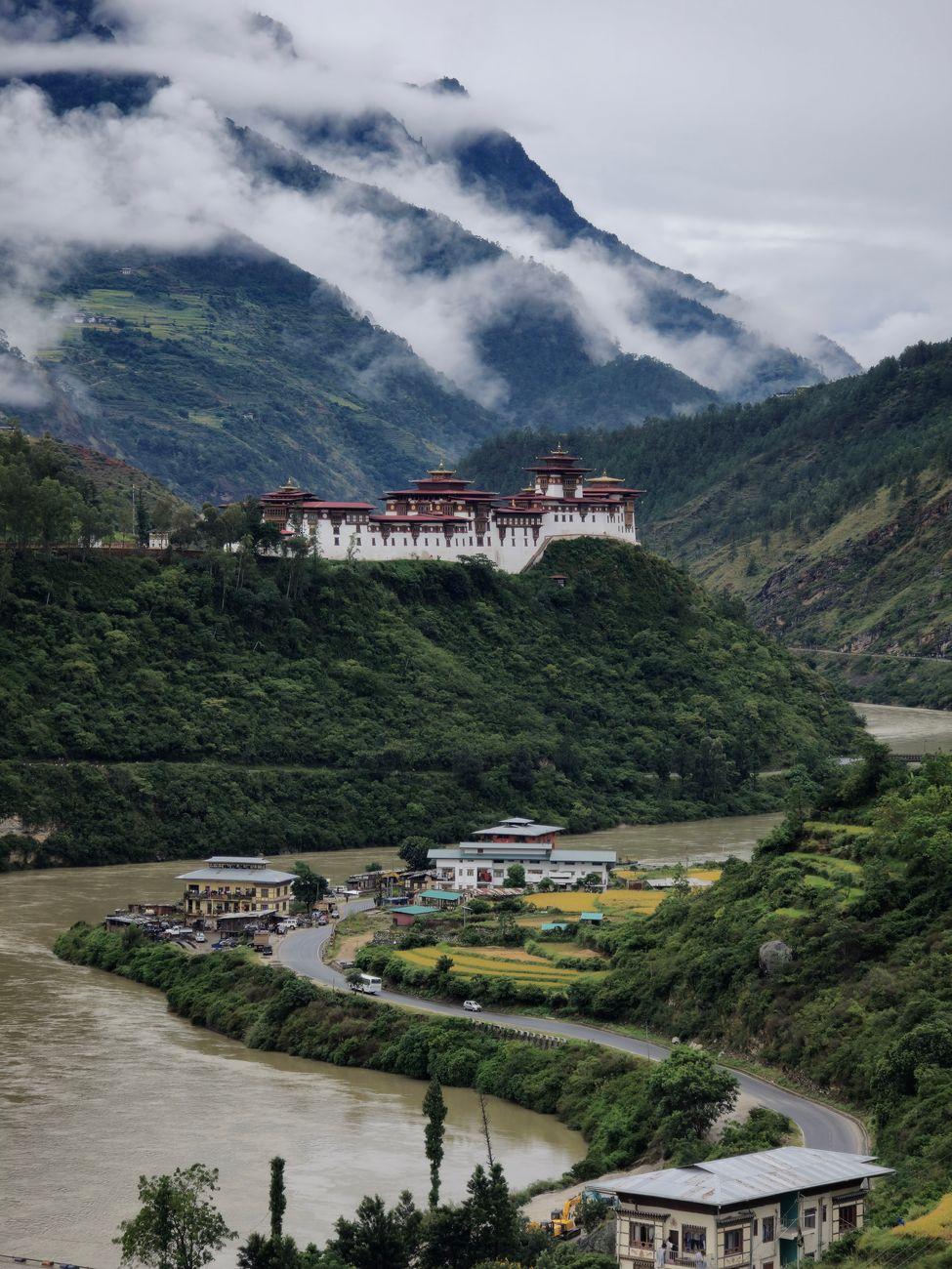 Majestic view of Punakha Dzong with clouds and river in Bhutan's lush landscape