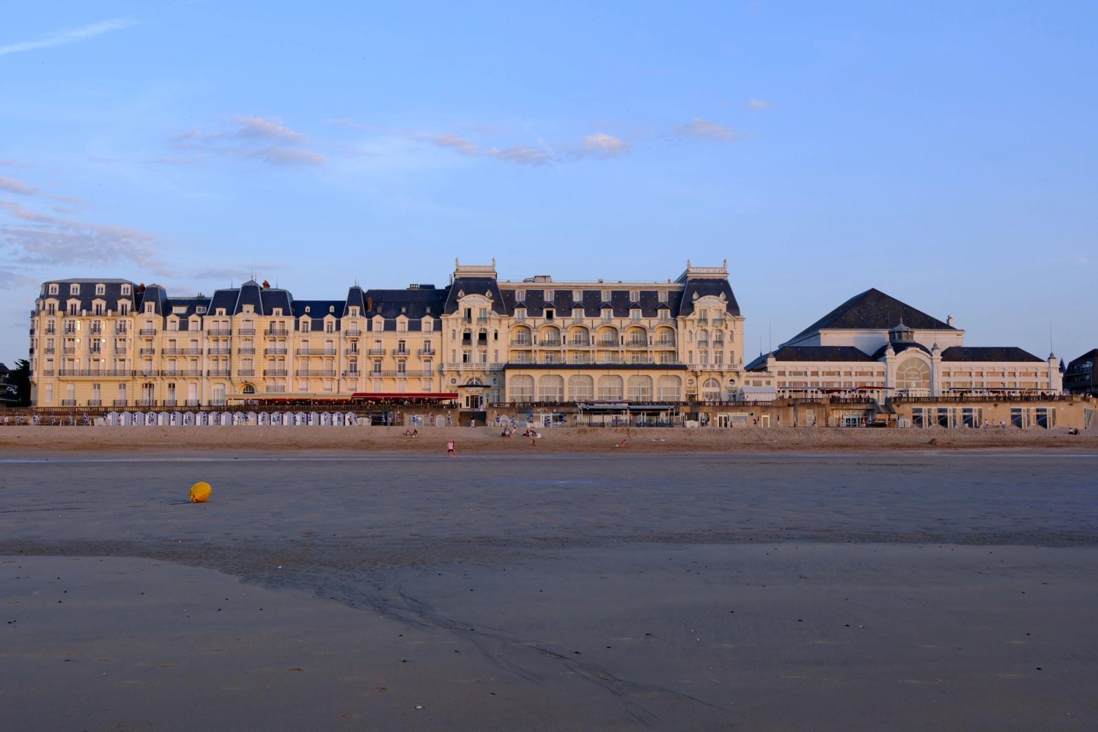 Elegant view of the Grand Hotel's facade on Cabourg Beach during sunset in Normandie, France