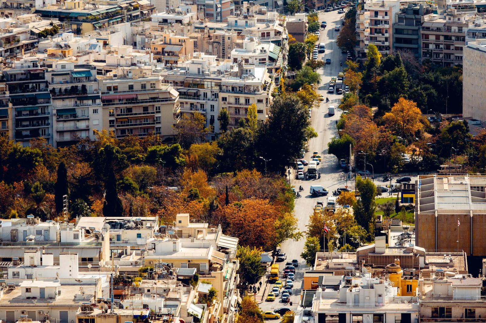 An aerial view of a tree-lined street cutting through dense apartment blocks