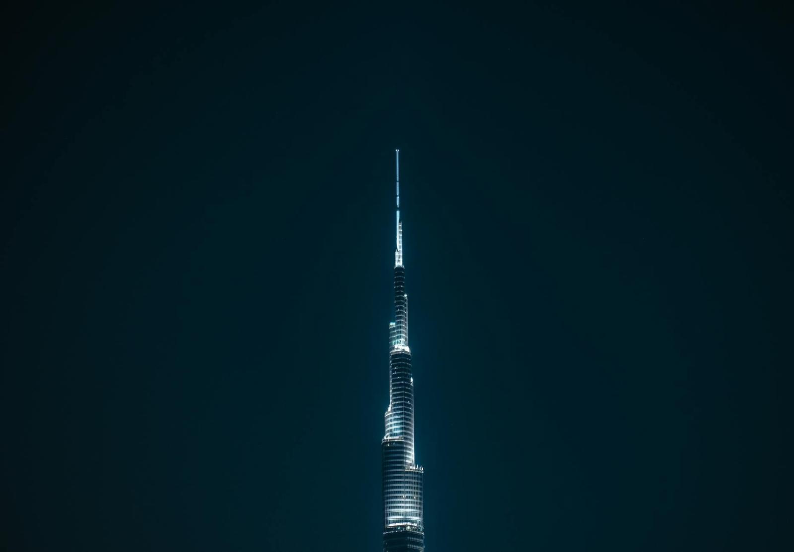 Illuminated skyscraper spire against a dark night sky