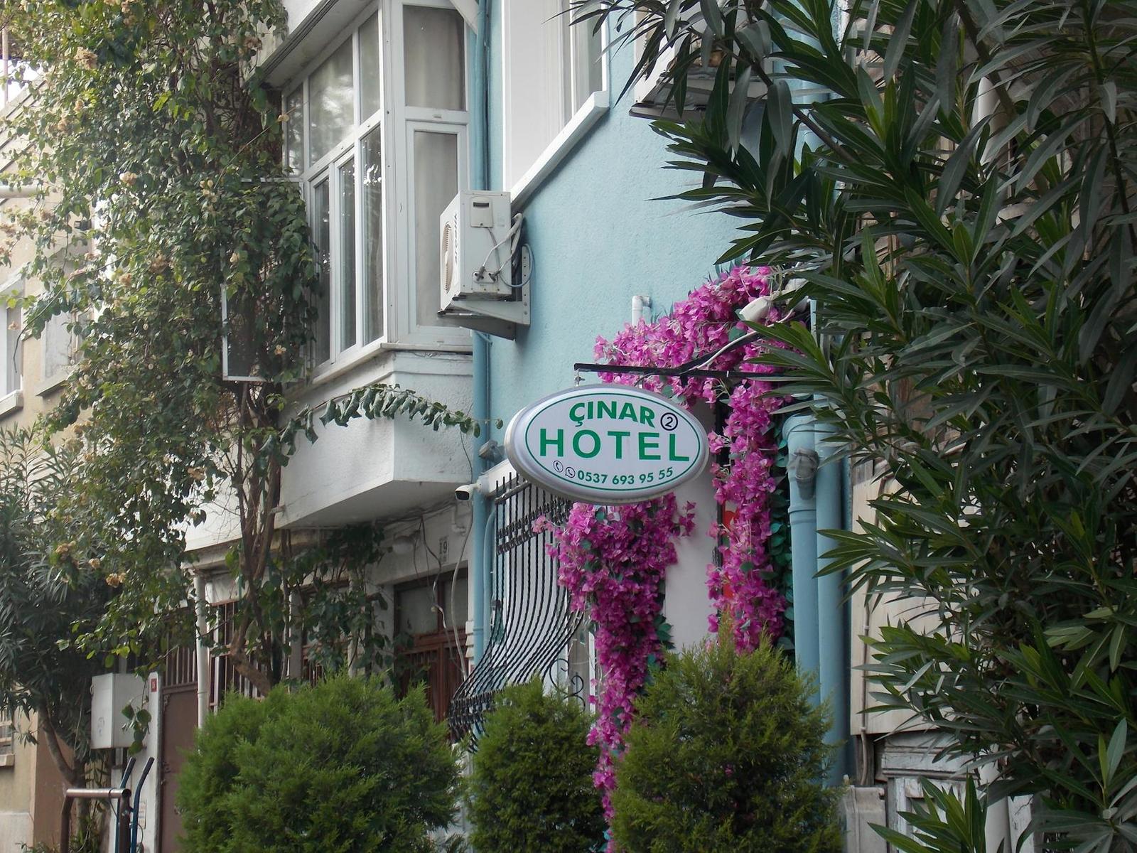Hotel entrance with a round sign framed by climbing bougainvillea