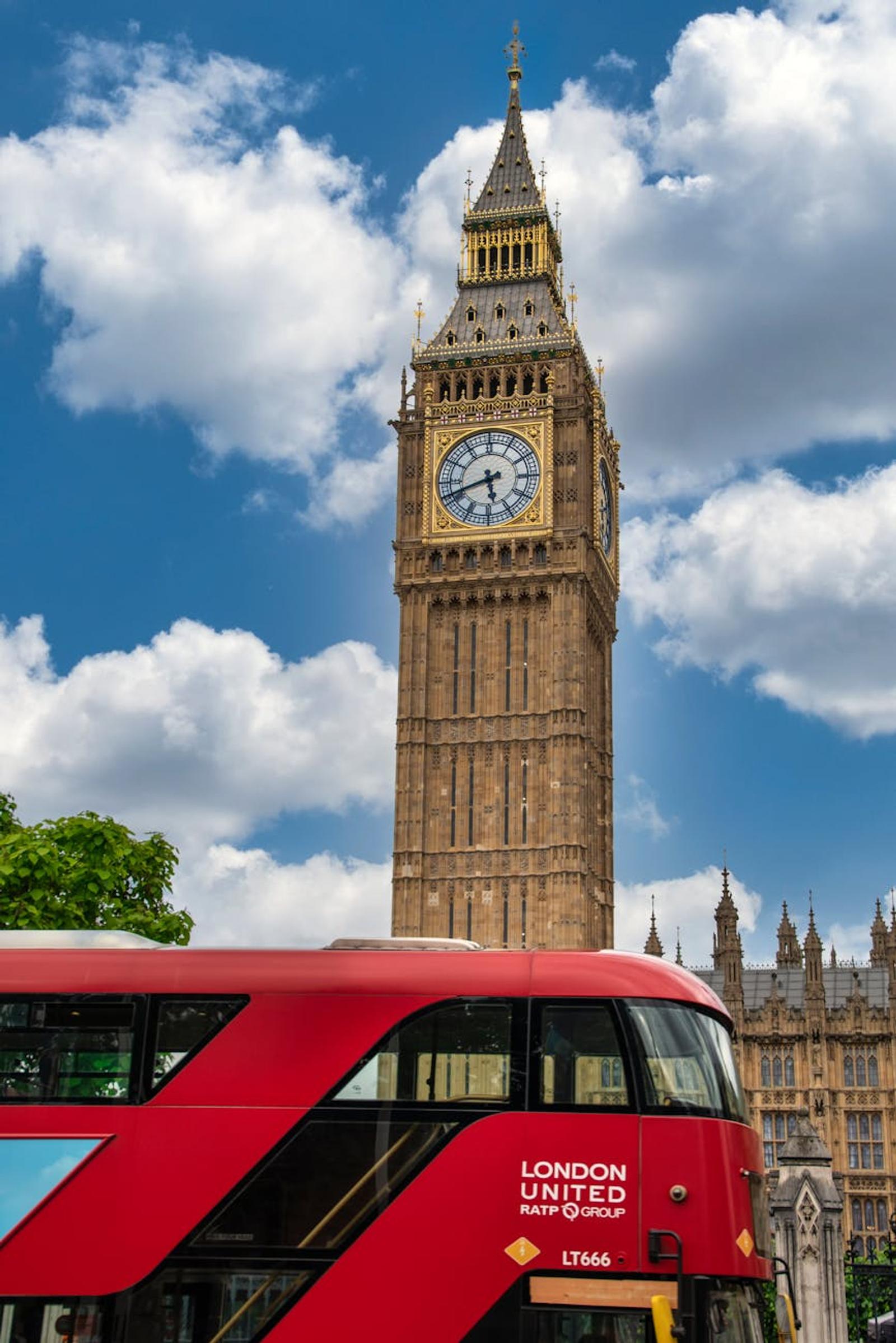 Big Ben and a red double-decker bus against a blue sky in London