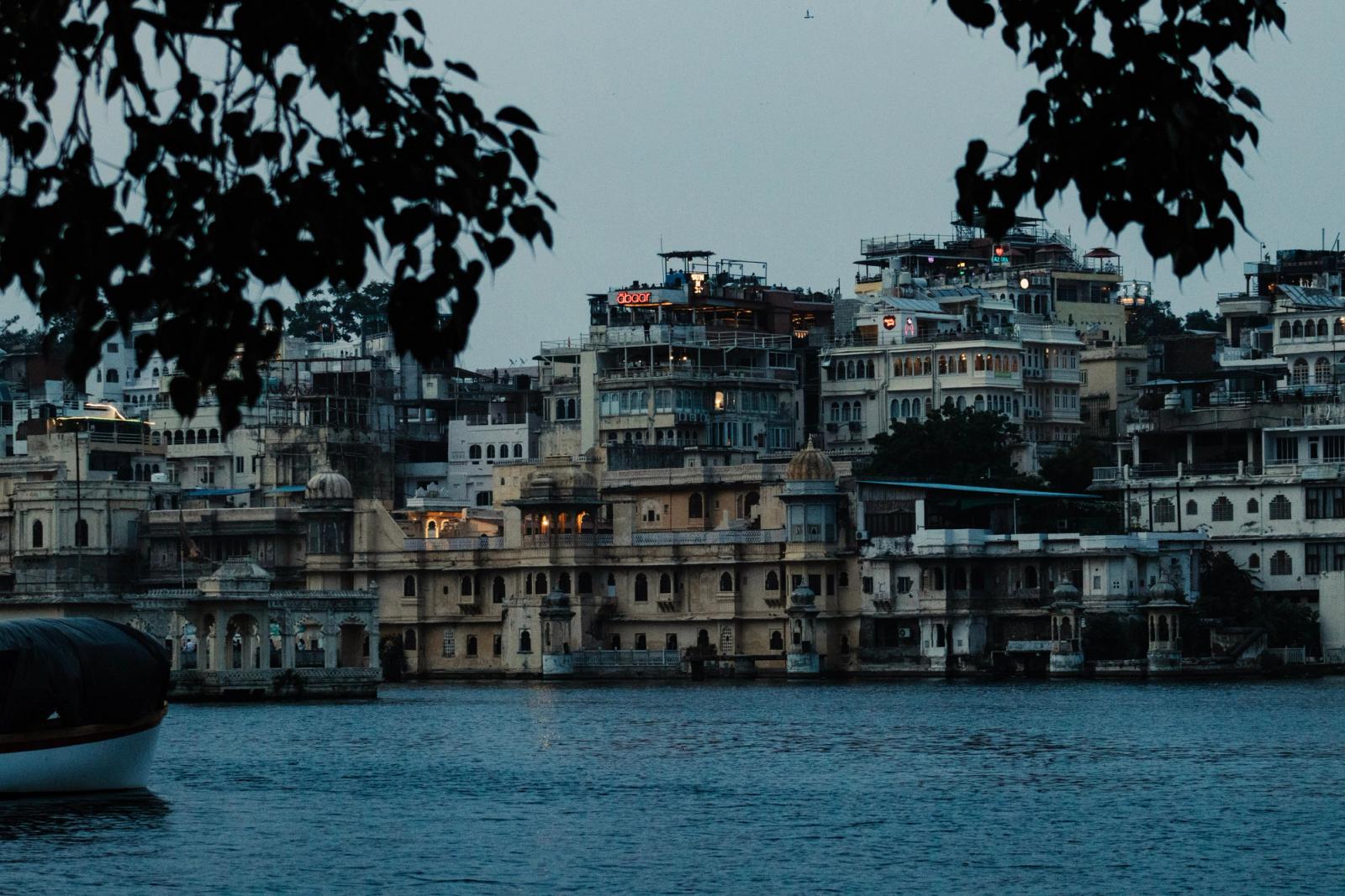 Lakeside buildings glowing at dusk framed by overhanging branches