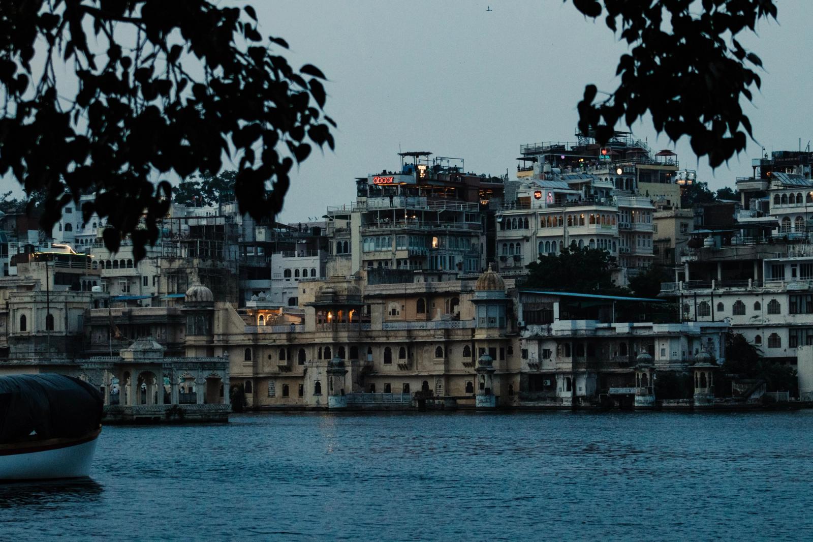 Lakeside buildings glowing at dusk framed by overhanging branches