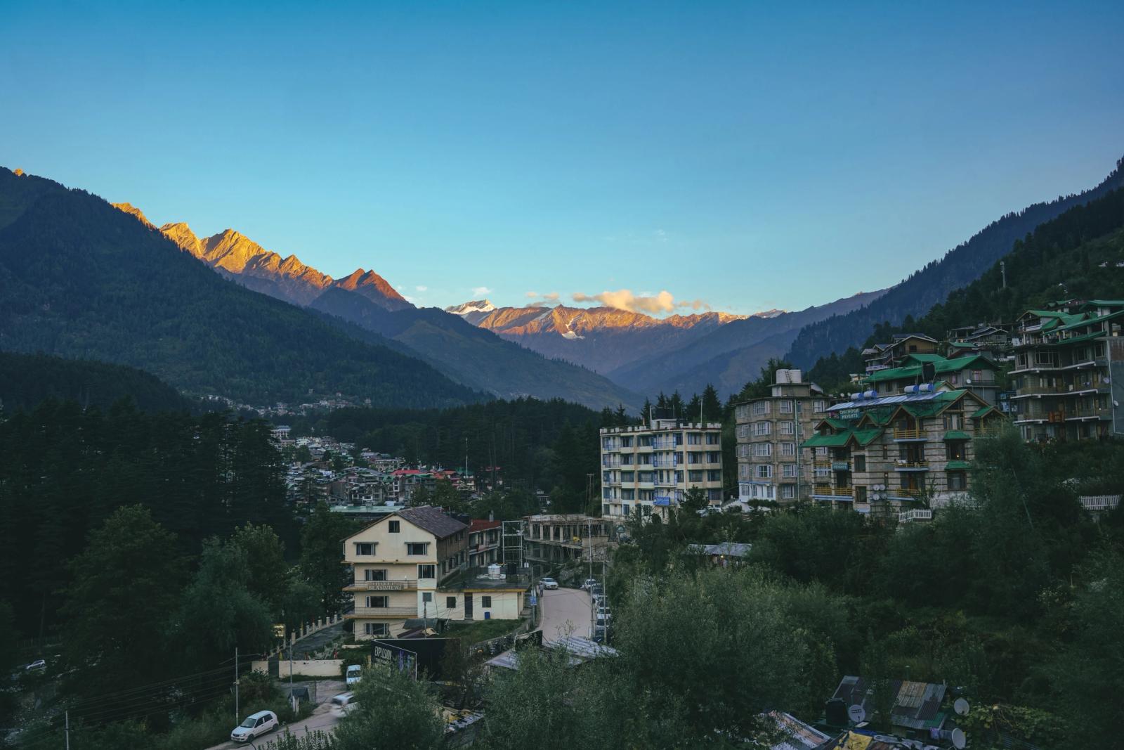 A mountain town nestled below snow-lit peaks at dusk