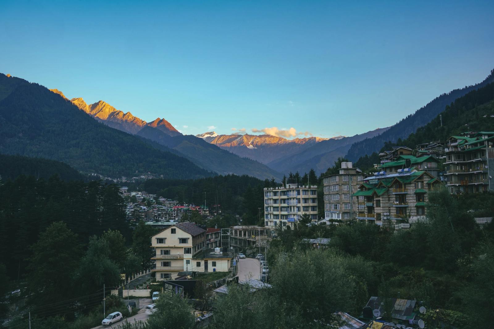 A mountain town nestled below snow-lit peaks at dusk