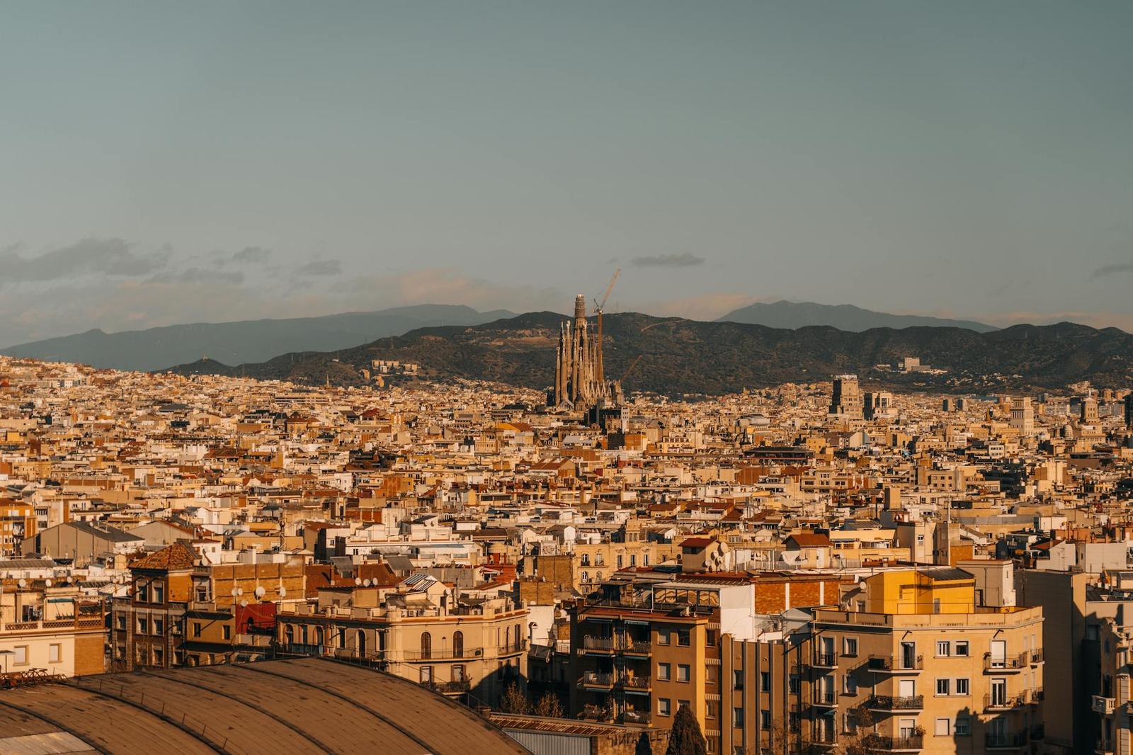 A dense terracotta rooftop skyline with tall spired towers rising above the city